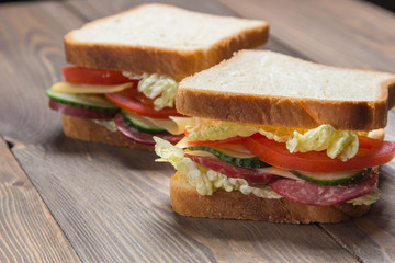 big sandwich with fresh vegetables on a wooden table and on a wood background