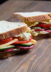big sandwich with fresh vegetables on a wooden table and on a wood background