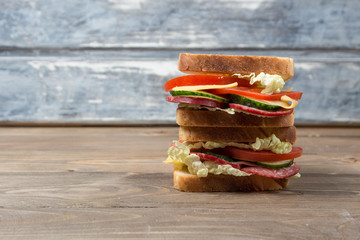 big sandwich with fresh vegetables on a wooden table and on a wood background