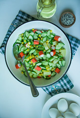 Salad with corn, crab sticks, cucumbers in a white bowl on a white background. Vegetarian salad. Cooking process.