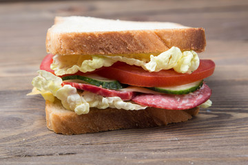 big sandwich with fresh vegetables on a wooden table and on a wood background