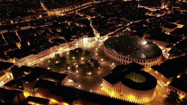 Aerial drone night video from iconic illuminated Arena theatre and City Hall in Bra square of beautiful city of Verona, Lombardy, Italy