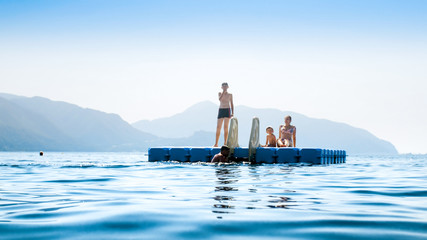 Family swimming and relaxing on floating pontoon at sea