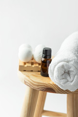 Handmade salt bath bombs in balls shape from organic vegan natural ingredients dark glass bottle with essential oil rolled white cotton terry towel on wood chair in bathroom. Spa wellness body care