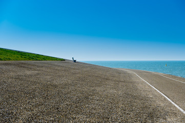 Obraz premium empty bench by sea with green grass and blue sky