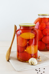 Marinated tomatoes in a jar on a light wooden table