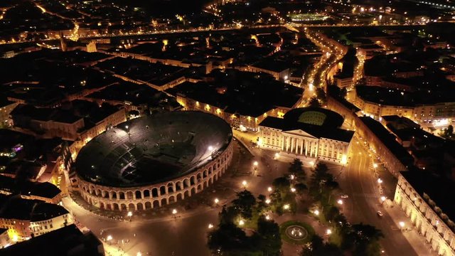 Aerial drone night video from iconic illuminated Arena theatre and City Hall in Bra square of beautiful city of Verona, Lombardy, Italy