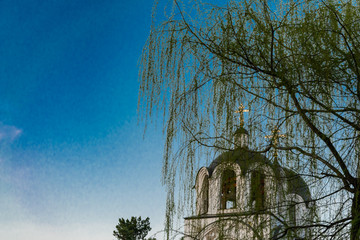 christian church against blue sky and willow branches