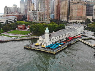 Naklejka premium Aerial view of Battery Park pier A leading to Liberty Island, people can be seen waiting in line for boarding as well as looking at Liberty Island located opposite to the docks