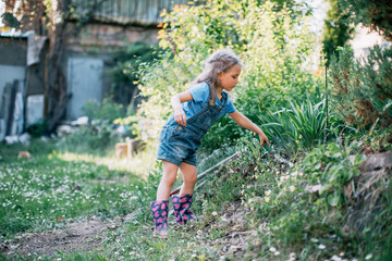 Naklejka na ściany i meble Little girl digging in the garden with trowel