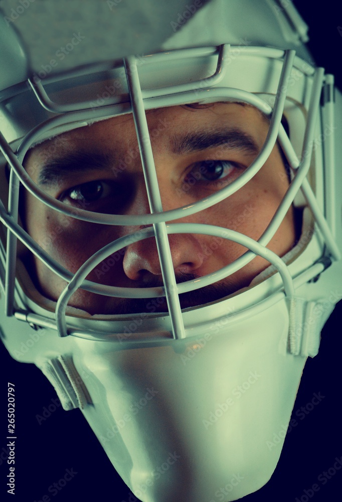 Wall mural Detail of a male face in a white goalie hockey mask.This is a detail hockey goalie. He is concentrated on game.