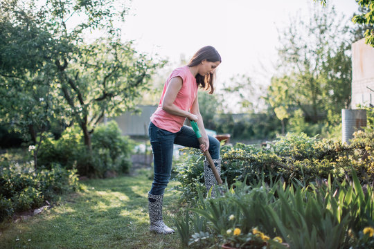 Young beautiful woman working in the garden with shovel