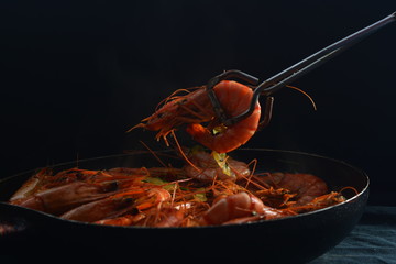 prawn in garlic and onion  sauce with olive oil in cooking pan on black background