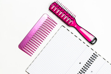 Pink hairbrush and a notebook on white background