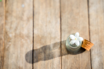 Glass bottles have small flowers on the wooden floor.
