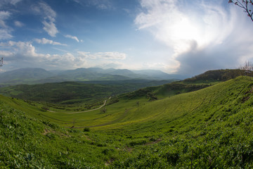 Fototapeta na wymiar Valley with green grass and mountains at background. Beautiful natural landscape in the summer time in Devichi, Azerbaijan.