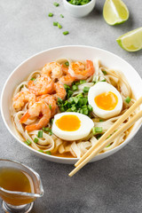 Japanese soup with wheat noodles, fried shrimp, soft-boiled egg with liquid yolk and green onions. Traditional Asian ramen, delicious lunch, healthy food