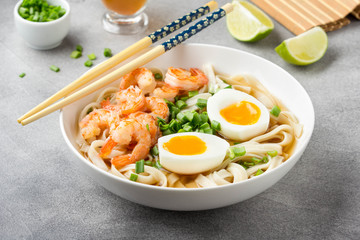 Japanese soup with wheat noodles, fried shrimp, soft-boiled egg with liquid yolk and green onions. Traditional Asian ramen, delicious lunch, healthy food