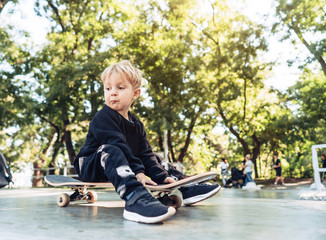 Young kid sitting in the park on a skateboard.