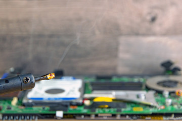 smoking soldering iron over a computer board with microchips