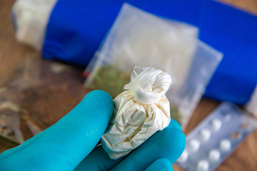 confiscation of drugs - bag of cocaine in the hand of a laboratory assistant on the background of a...