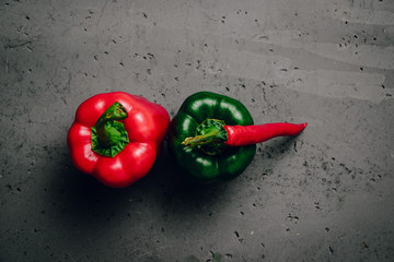 Chilli pepper and red, green pepper isolated on stone table. The concept of eating vegetables, providing vitamins and healthy eating. Comparison of red and green peppers.