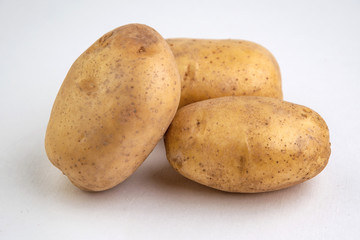 vegan diet: fresh raw organic potatoes, on white, short focus