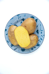 vegan diet: fresh raw organic potatoes on a plate, isolated on white, short focus