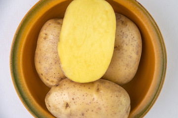 vegan diet: fresh raw organic potatoes on a plate, isolated on white, short focus