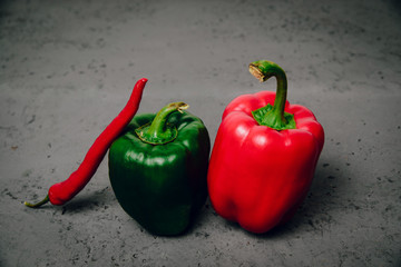 Green and red peppers on a dark background. The concept of preparing meals from vegetables, food for vegetarians, vegans. Healthy food, diet, healthy eating.