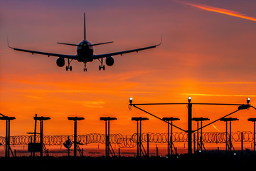 Passenger plane landing during orange sunset