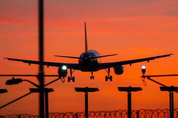 Passenger plane landing during orange sunset