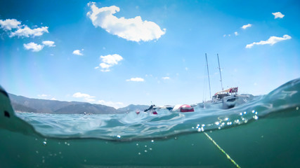 Image from under the water of yacht in sea against beautiful mountains