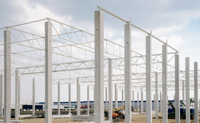 Concrete poles for the construction of the warehouse. Building a new warehouse, industrial concept and construction. Development and modernity. Setting stable pillars for new buildings.