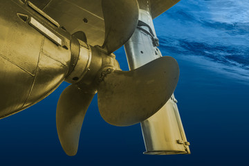 Propeller and rudder of big ship underway view from underwater. Close up image detail of ship.