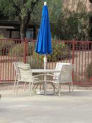 An umbrella, table, and seating area near a pool on a sunny day 