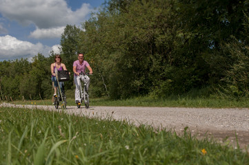 Young happy couple cycling on modern e-bikes in the nature