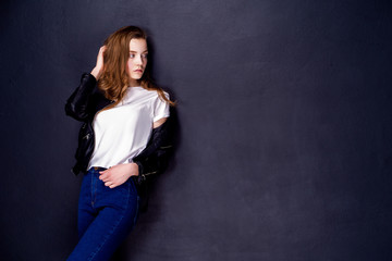 Young woman in white t-shirt and black leather jacket. Black studio wall background. Isolated.