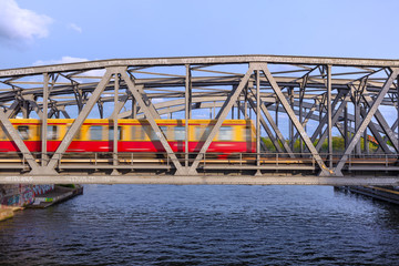 Obraz premium Berlin Treptow / Friedrichshain Ringbahnbrücke / Elsenbrücke Berliner S-Bahn fahrend / Treptow, Treptower Park, Spree Brücke Ringbahn s-bahn, fahrende Sbahn, Zug zum BER, Verbindung Berliner Flughafen
