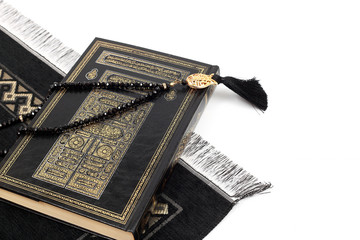Islamic Holy Book Quran with rosary beads and prayer rug on isolated white background. Kuran the holy book of Muslims. Ramadan concept.