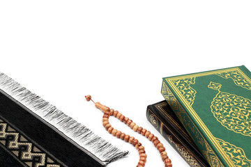 Islamic Holy Book Quran with rosary beads and prayer rug on isolated white background. Kuran the holy book of Muslims. Ramadan concept.