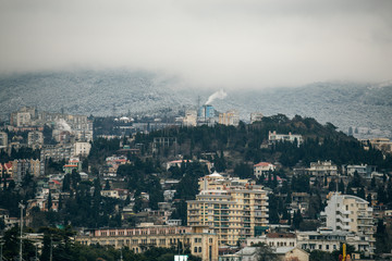 Yalta city resort downtown with buildings on hills and foggy mountains at background in cloudy winter day