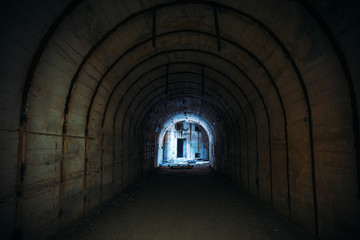 Long underground tunnel with light in end. Concrete corridor of abandoned bunker