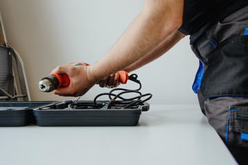 The worker opens the toolbox and pulls out the drill. The concept of work, hiring a professional. Preparing for work, drilling, renovation at home.