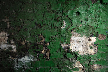 Background texture of old brick wall with shabby green paint and cracked plaster