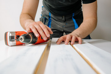 The man wraps wooden boards on the work table. The concept of DIY and renovation of new things. A man tinkering at home, working with wood.