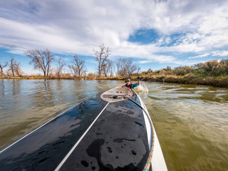 man swimming behind paddleboard