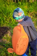 A little boy pours water from the watering can. Watering the beds. Gardening