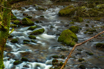 Fototapeta na wymiar Water streaming through the rocks downhill creating a small waterfall.