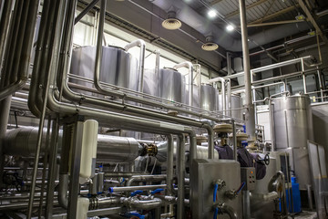 Stainless steel brewing equipment, large reservoirs or tanks and pipes in modern beer factory. Brewery production concept, industrial background